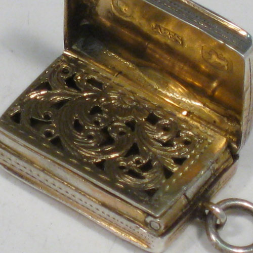 Antique Victorian sterling silver vinaigrette, having a rectangular body with with engine-engraved decoration and a vacant cartouche, a hinged lid, a gold-gilt interior with hinged hand-pierced and chased grill, and a side ring. Made by Aston & Son, of Birmingham in 1858. The dimensions of this fine hand-made silver vinaigrette are length 2 cms (0.75 inches), and width 1.5 cms (0.5 inches).