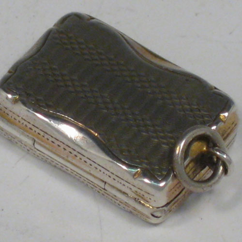 Antique Victorian sterling silver vinaigrette, having a rectangular body with with engine-engraved decoration and a vacant cartouche, a hinged lid, a gold-gilt interior with hinged hand-pierced and chased grill, and a side ring. Made by Aston & Son, of Birmingham in 1858. The dimensions of this fine hand-made silver vinaigrette are length 2 cms (0.75 inches), and width 1.5 cms (0.5 inches).