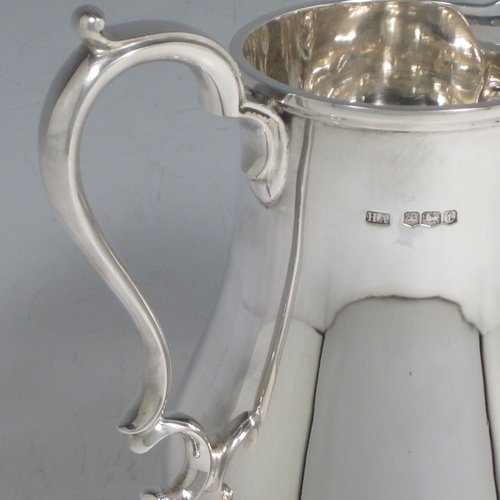 Sterling silver water jug, in a George I beer jug style, having a plain round bellied body, sparrow-beak spout, scroll handle, and sitting on a pedestal foot. Made by Henry Atkins of Sheffield in 1936. The dimensions of this fine hand-made silver water jug are height 21 cms (8.25 inches), length 16.5 cms (6.5 inches), length 14 cms (5.5 inches), and it weighs approx. 449g (14.5 troy ounces). Please note that this silver water jugs size would be perfect for serving two people.