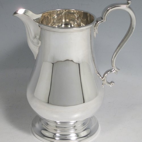 Sterling silver water jug, in a George I beer jug style, having a plain round bellied body, sparrow-beak spout, scroll handle, and sitting on a pedestal foot. Made by Henry Atkins of Sheffield in 1936. The dimensions of this fine hand-made silver water jug are height 21 cms (8.25 inches), length 16.5 cms (6.5 inches), length 14 cms (5.5 inches), and it weighs approx. 449g (14.5 troy ounces). Please note that this silver water jugs size would be perfect for serving two people.