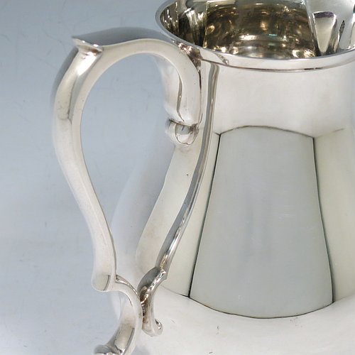 A Sterling Silver water jug, in a George I beer jug style, having a plain round bellied body, sparrow-beak spout, scroll handle, and sitting on a pedestal foot. Made by Robert Comyns of London in 1939. The dimensions of this fine hand-made silver water jug are height 17 cms (6.75 inches), length 16.5 cms (6.5 inches), length 16 cms (6.25 inches), and it weighs approx. 465g (15 troy ounces).