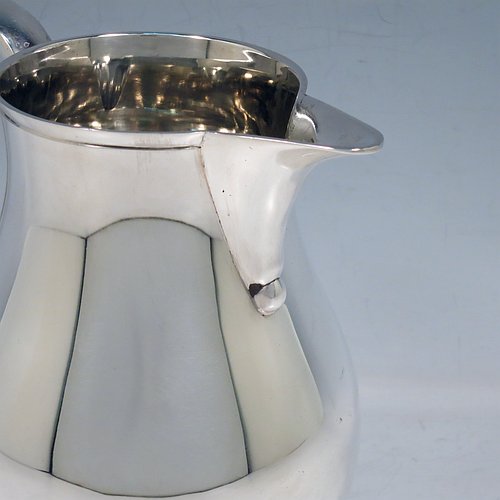 A Sterling Silver water jug, in a George I beer jug style, having a plain round bellied body, sparrow-beak spout, scroll handle, and sitting on a pedestal foot. Made by Robert Comyns of London in 1939. The dimensions of this fine hand-made silver water jug are height 17 cms (6.75 inches), length 16.5 cms (6.5 inches), length 16 cms (6.25 inches), and it weighs approx. 465g (15 troy ounces).