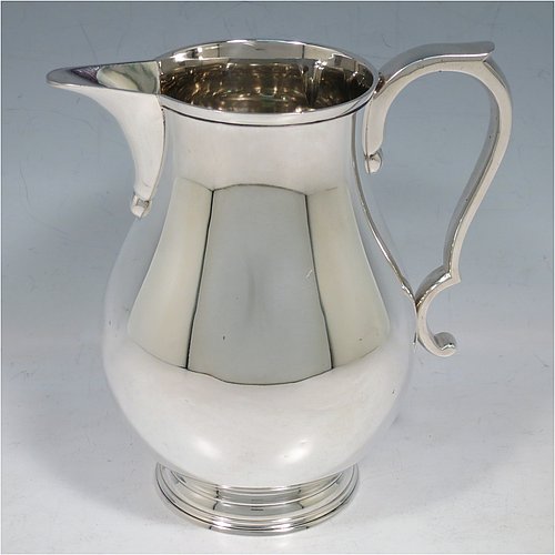 A Sterling Silver water jug, in a George I beer jug style, having a plain round bellied body, sparrow-beak spout, scroll handle, and sitting on a pedestal foot. Made by Robert Comyns of London in 1939. The dimensions of this fine hand-made silver water jug are height 17 cms (6.75 inches), length 16.5 cms (6.5 inches), length 16 cms (6.25 inches), and it weighs approx. 465g (15 troy ounces).