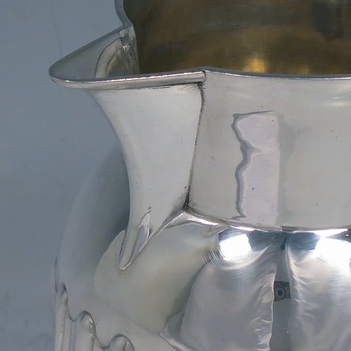 An Antique Georgian Sterling Silver water or beer jug, having a round bellied body with hand-chased swirl-fluted decoration, sparrow-beak spout, scroll handle, and sitting on a collet foot. Made by William Grundy of London in 1765. The dimensions of this fine hand-made antique silver water or beer jug are height 13.5 cms (5.3 inches), length 15 cms (6 inches), and it weighs approx. 372g (12 troy ounces).   