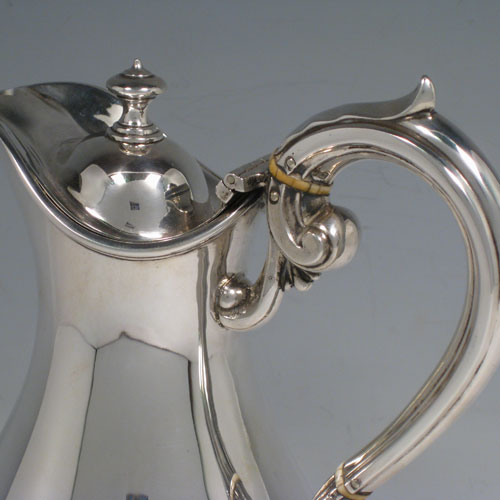    Antique Victorian sterling silver water jug, having a plain round baluster ewer-shaped body, with hinged lid and finial, insulated scroll handle, and sitting on a pedestal foot. Made by Martin Hall of London in 1873. Height 21.5 (8.5 inches), length 14.5 cms (5.75 inches). Weight approx. 444g (14.3 troy ounces).