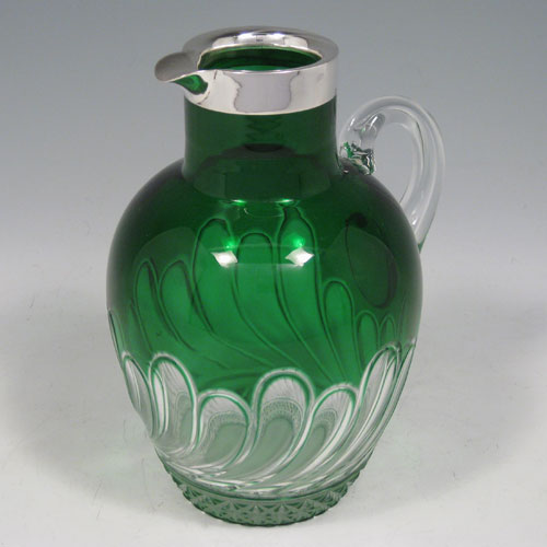    Sterling silver and hand-cut green coloured crystal, with loop handle and swirl-fluted clear glass decoration. Made by John Grinsell of Birmingham in 1918. Height 18 cms (7.25 inches), length 14 cms (5.5 inches).