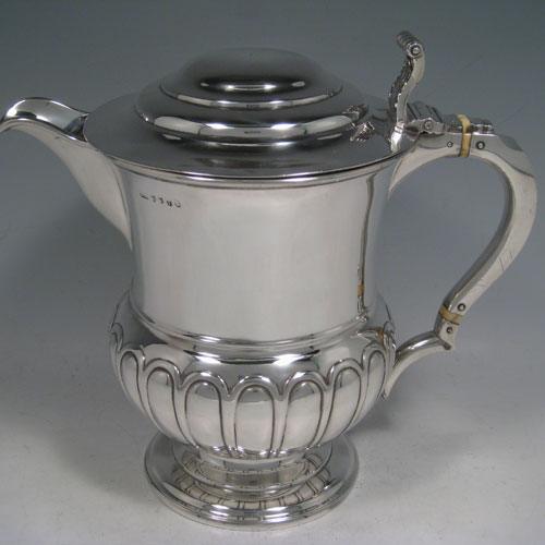 A large and very handsome Antique Georgian Sterling Silver water or beer jug, having a round body with hand-chased half-fluted decoration, plain pouring spout, an insulated scroll handle, a hinged domed lid with cast acanthus leaf thumb-piece, and sitting on a plain round pedestal foot. Made by J. McKay of Edinburgh in 1811. The dimensions of this fine hand-made antique silver beer or water jug are height 23 cms (9 inches), length 26 cms (10.25 inches), and it weighs approx. 991g (32 troy ounces)