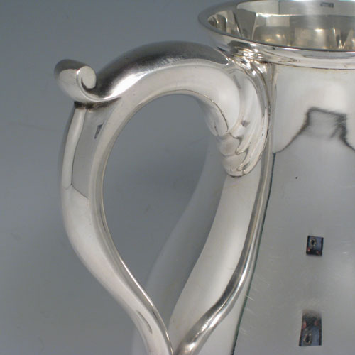 Sterling silver large water jug, in a George I beer jug style, having a plain round bellied body, sparrow-beak spout, scroll handle, and sitting on a pedestal foot. Made in North America in ca. 1930. Height 21 cms (8.25 inches), length 18.5 cms (7.25 inches). Weight approx. 807g (26 troy ounces).