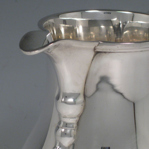 Sterling silver large water jug, in a George I beer jug style, having a plain round bellied body, sparrow-beak spout, scroll handle, and sitting on a pedestal foot. Made in North America in ca. 1930. Height 21 cms (8.25 inches), length 18.5 cms (7.25 inches). Weight approx. 807g (26 troy ounces).