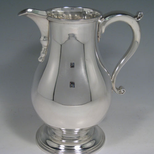 Sterling silver large water jug, in a George I beer jug style, having a plain round bellied body, sparrow-beak spout, scroll handle, and sitting on a pedestal foot. Made in North America in ca. 1930. Height 21 cms (8.25 inches), length 18.5 cms (7.25 inches). Weight approx. 807g (26 troy ounces).