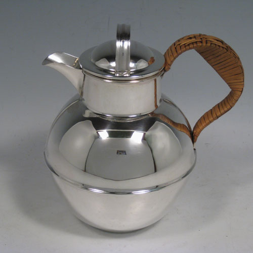 Sterling silver Guernsey style water / milk jug, having a plain round body, with pull-off lid, and insulated wicker-work handle. Made by William Henry Jackson of Birmingham in 1933. Height 16 cms (6.25 inches), length 14 cms (5.5 inches). Weight approx. 293g (9.5 troy ounces).