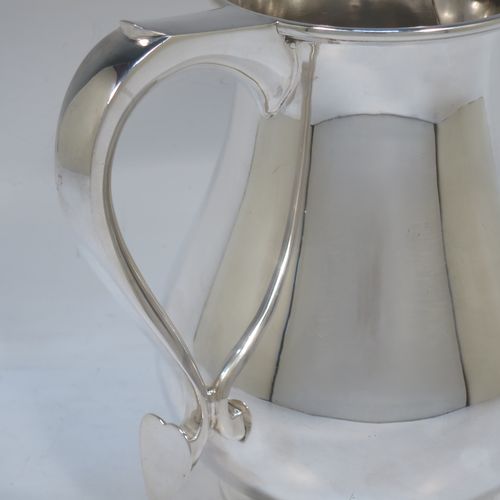 A very handsome and large Sterling Silver water jug, in a George I beer jug style, having a plain round bellied body, sparrow-beak spout, a scroll handle, and sitting on a collet foot. Made by Edward Barnard of London in 1975. The dimensions of this fine hand-made silver water jug are height 18 cms (7 inches), length 19 cms (7.5 inches), capacity of 1.5 litres (2.64 pints) and it weighs approx. 747g (24 troy ounces).  