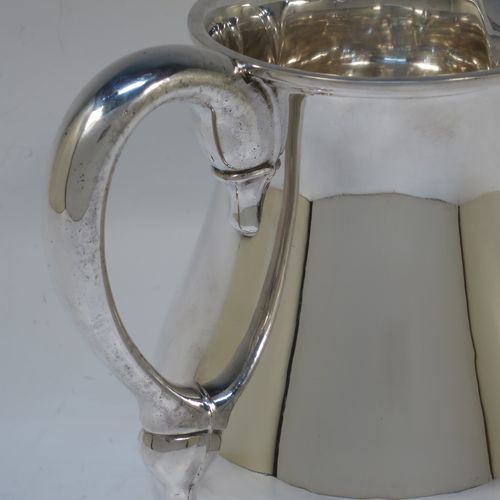 A very handsome American Sterling Silver water jug, in a George I beer jug style, having a plain round bellied body, sparrow-beak spout, a scroll handle, and sitting on a collet foot. Made in ca. 1930 in North America. The dimensions of this fine hand-made silver water jug are height 16.5 cms (6.5 inches), length 16 cms (6.25 inches), and it weighs approx. 512g (16.5 troy ounces).   