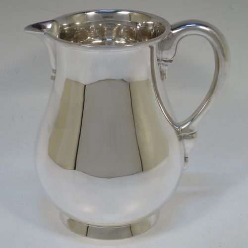 A very handsome American Sterling Silver water jug, in a George I beer jug style, having a plain round bellied body, sparrow-beak spout, a scroll handle, and sitting on a collet foot. Made in ca. 1930 in North America. The dimensions of this fine hand-made silver water jug are height 16.5 cms (6.5 inches), length 16 cms (6.25 inches), and it weighs approx. 512g (16.5 troy ounces).   