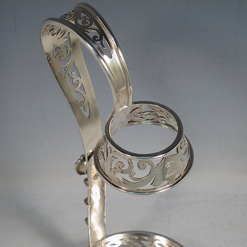 An Antique Victorian Silver Plated wine bottle cradle or holder, having a round straight-sided base with hand-pierced floral decoration, a sliding scroll handle with matching neck and floral retaining screw. Made by Elkington & Co., of Sheffield in ca. 1880. The dimensions of this fine hand-made antique silver-plated wine bottle holder or cradle are height 28 cms (11 inches), and diameter of base 10 cms (4 inches). Please note that this wine bottle cradle or holder will accept a 75cl bottle, (bottle shown for display purposes only).