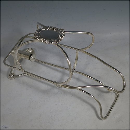 An Antique Victorian Silver Plated wine bottle cradle or holder, having a wire-work body with a cast wine-label style cartouche attached to the handle, and sitting on a base with two cushion feet. Made in Sheffield in ca. 1880. The dimensions of this fine hand-made antique silver wine bottle holder or cradle are length 24 cms (9.5 inches), width 10 cms (4 inches), and height 16.5 cms (6.5 inches). Please note that this wine bottle cradle will accept a standard 75cl, (bottle shown for display purposes only).    