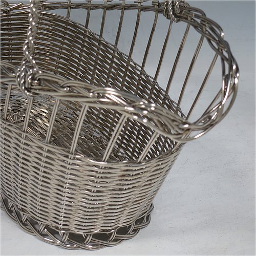 An Antique Victorian Silver Plated wine bottle cradle or holder, having an oval straight-sided body with tapering sides, with an attached carrying handle, and sitting on a flat base, all made in a basket-weave style with individual wire-work decoration. Made in Sheffield in ca. 1900. The dimensions of this fine hand-made antique silver wine bottle holder or cradle are length 23 cms (9 inches), width 12 cms (4.75 inches), and height 18 cms (7 inches). Please note that this wine bottle cradle will accept a standard 75cl, (bottle shown for display purposes only).    