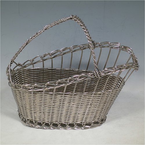 An Antique Victorian Silver Plated wine bottle cradle or holder, having an oval straight-sided body with tapering sides, with an attached carrying handle, and sitting on a flat base, all made in a basket-weave style with individual wire-work decoration. Made in Sheffield in ca. 1900. The dimensions of this fine hand-made antique silver wine bottle holder or cradle are length 23 cms (9 inches), width 12 cms (4.75 inches), and height 18 cms (7 inches). Please note that this wine bottle cradle will accept a standard 75cl, (bottle shown for display purposes only).    