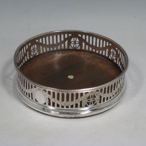    Antique Georgian sterling silver pair of Neoclassical wine coasters, having hand-pierced walls with acanthus-leaf swags, applied bead-edge borders, and oak bases with ivory buttons. Made by Robert Hennell of London in 1776. Diameter 12.5 cms (5 inches), height 3.5 cms (1.3 inches).