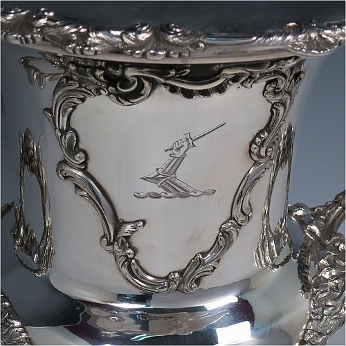 An Antique Georgian Old Sheffield plated wine cooler, in the Campagna style, with cast floral borders, a pair of cast anthemion leaf handles, and applied scroll cartouches either side. All with original interior and cover. Made in ca. 1835. The dimensions of this fine hand-made antique Old Sheffield plated wine cooler are height 30.5 cms (12 inches), width across handles 26 cms (10.25inches). Please note that this item is crested on one side.   