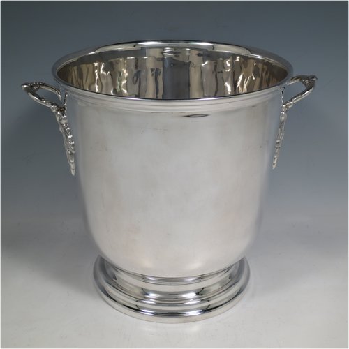 A Sterling Silver wine bottle cooler / trophy cup, having a plain round baluster body, with two cast handles with grape-vine decoration, and sitting on a collet foot. Made by Roberts & Belk of Sheffield in 1982. The dimensions of this fine hand-made silver wine cooler are height 19 cms (7.5 inches), and it weighs approx. 1,193g (38.5 troy ounces)   