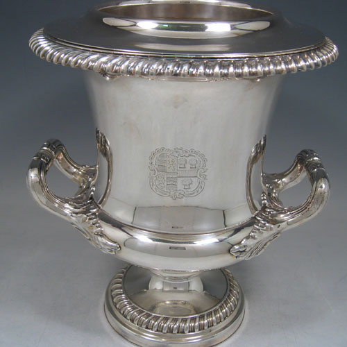 A very hansome pair of Antique Georgian Old Sheffield silver-plated wine coolers in the Campana style, with applied garoon borders, two side-handles with anthemion leaf mounts, with original interiors and covers, and all sitting on pedestal feet. Made in ca. 1815. The dimensions of this fine pair of hand-made antique Old Sheffield silver plated wine coolers are height 27 cms (10.5 inches), width across handles 24 cms (9.5 inches). Please note that these items are crested.