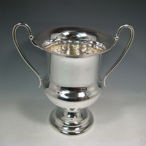 Sterling silver large wine bottle cooler / trophy cup, having a plain round baluster body, with two scroll handles, and sitting on a pedestal foot. Made by Catchpole and Williams of London in 1925. Height 36 cms (14.25 inches), spread across arms 35 cms (13.75 inches). Weight approx. 1,560g (50.3 troy ounces)