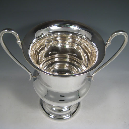 Sterling silver large wine bottle cooler / trophy cup, having a plain round baluster body, with two scroll handles, and sitting on a pedestal foot. Made by Catchpole and Williams of London in 1925. Height 36 cms (14.25 inches), spread across arms 35 cms (13.75 inches). Weight approx. 1,560g (50.3 troy ounces)