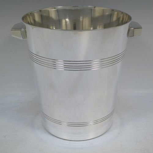 A very handsome Art Deco style Silver Plated wine bottle cooler, having a plain round body with tapering sides, with two cast angular side-handles, and two bands of hand-chased reeded decoration, all sitting on a flat base. Made in ca. 1930. The dimensions of this fine hand-made silver-plated  wine cooler are height 21 cms (8.25 inches), and diameter at lip 18.5 cms (7.25 inches). Please note that this will easily hold a magnum size bottle.