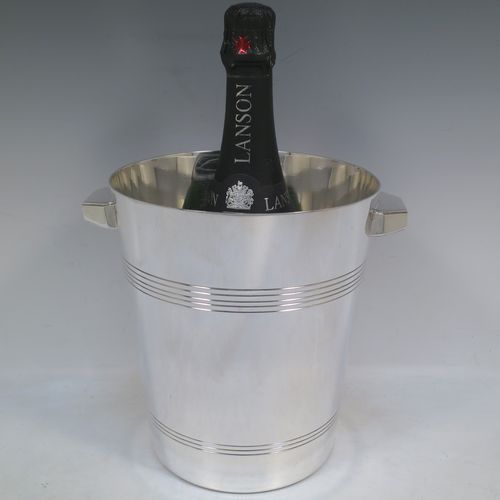 A very handsome Art Deco style Silver Plated wine bottle cooler, having a plain round body with tapering sides, with two cast angular side-handles, and two bands of hand-chased reeded decoration, all sitting on a flat base. Made in ca. 1930. The dimensions of this fine hand-made silver-plated  wine cooler are height 21 cms (8.25 inches), and diameter at lip 18.5 cms (7.25 inches). Please note that this will easily hold a magnum size bottle.