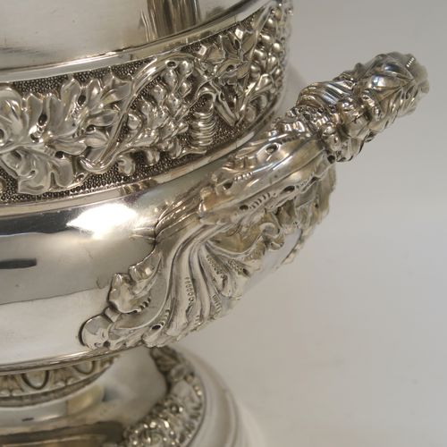 A very handsome Antique Georgian Old Sheffield plated wine cooler, in the Campagna style, with cast gadroon, scroll, and floral borders, a pair of cast side-handles, with a central applied band of grape-vine work, with its original tin-backed interior liner and cover, and all sitting on a pedestal foot. This beautiful antique Old Sheffield plated wine cooler was made in ca. 1825. The dimensions of this fine hand-made antique Old Sheffield wine cooler are height 23 cms (9 inches), and width across handles 26 cms (10.25 inches).  