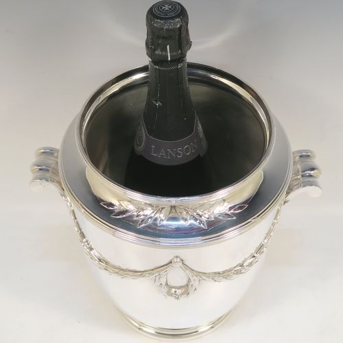 A very elegant Neoclassical style Antique Victorian silver-plated wine cooler, having a plain round body with tapering sides, with beautiful applied acanthus leaf swags, two cast scroll side-handles, and all sitting on a pedestal foot. This handsome antique silver plated wine bottle cooler was made in ca. 1880. The dimensions of this fine hand-made antique silver wine cooler are height 24 cms (9.5 inches), width across handles 25.5 cms (10 inches).   