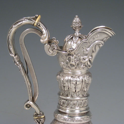 Antique Victorian sterling silver wine ewer, having a round body with hand-chased floral work, swirl fluting, and oval panels with a vacant cartouche, with a hinged lid and pineapple finial attached to a foliate mechanised handle, and all sitting on a pedestal foot with bead border. Made by Martin and Hall of Sheffield in 1868. Height 32 cms (12.5 inches), length 16.5 cms (6.5 inches). Weight approx. 982g (31.7 troy ounces).