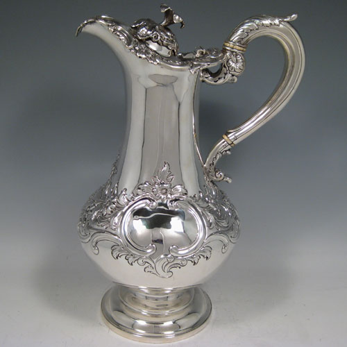 A large and very handsome Antique Victorian Sterling Silver ewer, having a bellied body with hand-chased floral decoration, an insulated scroll handle with anthemion thumb-piece, a hinge lid with a cast floral finial, a spout with an applied cast floral border, and all sitting on a plain round pedestal foot. This beautiful antique silver wine ewer was made by Leond Urquart of Edinburgh in 1837. The dimensions of this fine hand-made silver ewer are height 30 cms (12 inches), length 20 cms (8 inches), and it weighs approx. 1,116g (36 troy ounces).