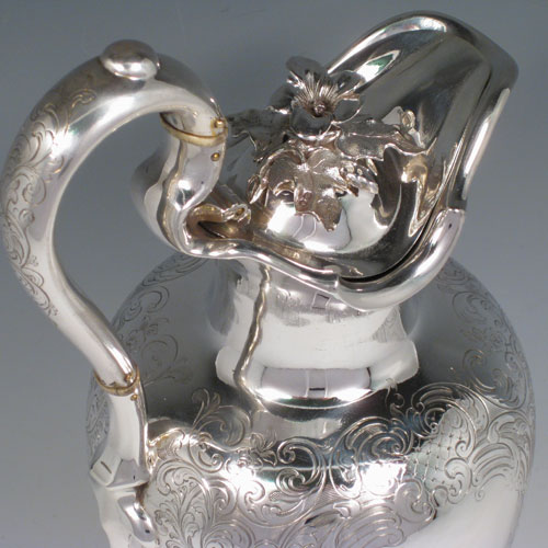 Antique Victorian sterling silver wine ewer with hand-engraved floral decoration, hinged lid with cast flower finial, insulated scroll handle, and sitting on a pedestal foot. Made by the Barnard Brothers of London in 1845. Height 35 cms (13.75 inches), length 16 cms (6.25 inches). Weight approx. 905g (29.2 troy ounces).